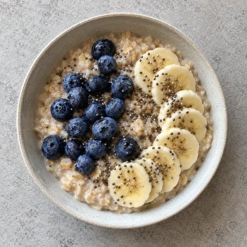 A bowl of oatmeal topped with blueberries, banana slices and chia seeds